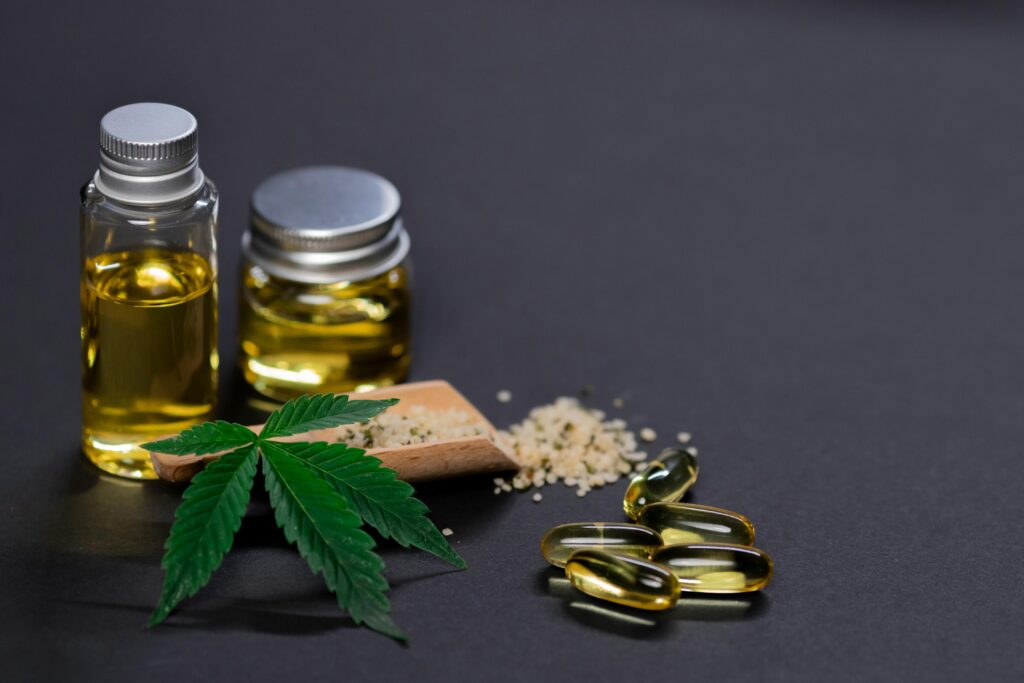 Hemp oil with hemp seeds and capsules, behind a cannabis leaf